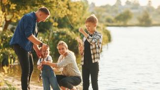 Family of four fishing on the edge of a lake